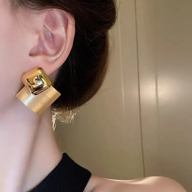 Women's gold brushed square stud earrings with 925 silver needle posts on a light background