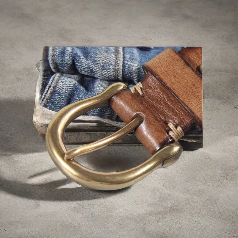 Men's black cattlehide leather belt with a copper pin buckle on a jeans background.
