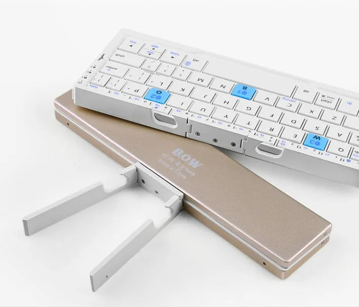 Mini foldable Bluetooth keyboard in black, open next to a smartphone on a wooden desk