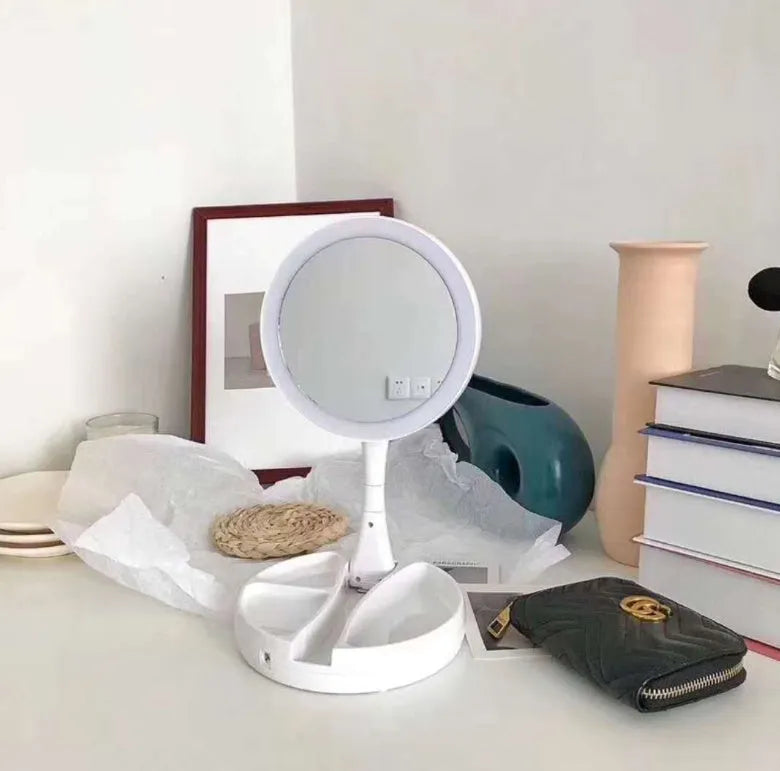 White foldable LED vanity mirror with USB charging port and built-in storage compartments on a table.