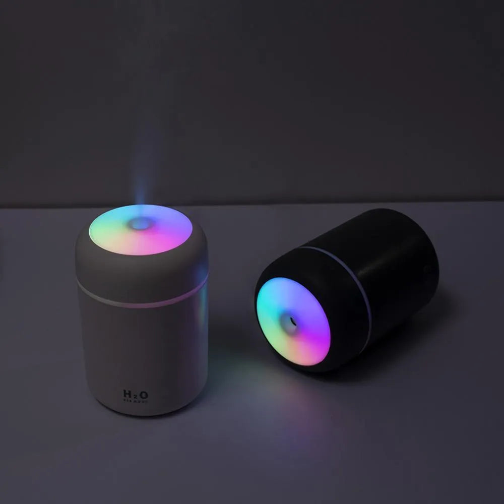 Pink USB-powered mini humidifier with colourful lights on a wooden desk