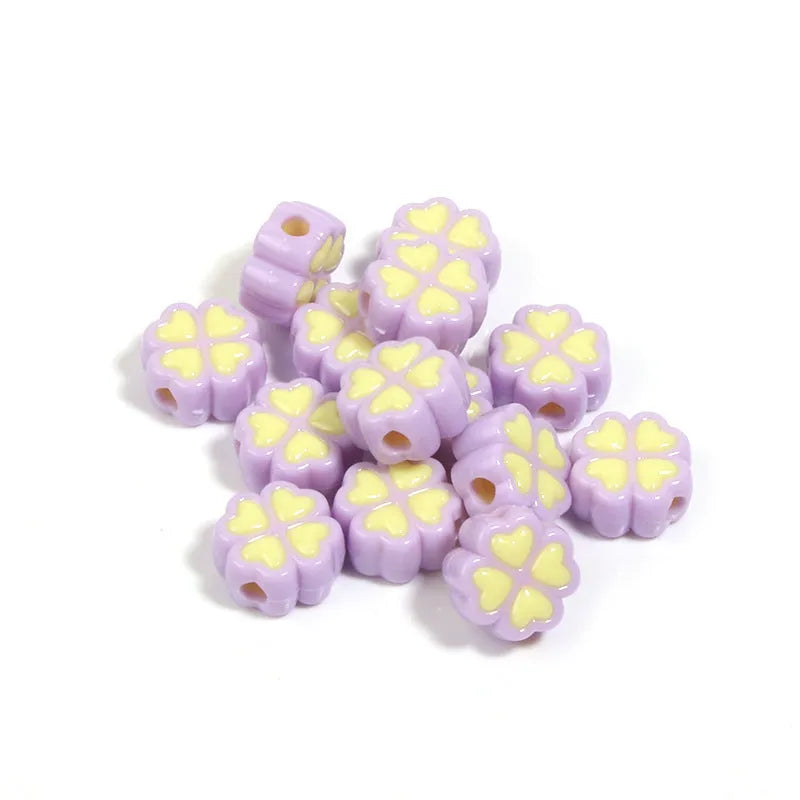 A selection of 15mm frosted acrylic beads showing a raised cartoon love and four-leaf clover pattern in various colours.