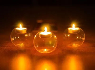 Handmade round hollow glass candle ball in three sizes on a table.