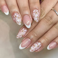 Short almond-shaped false nails with French tips and glitter powder flower decoration