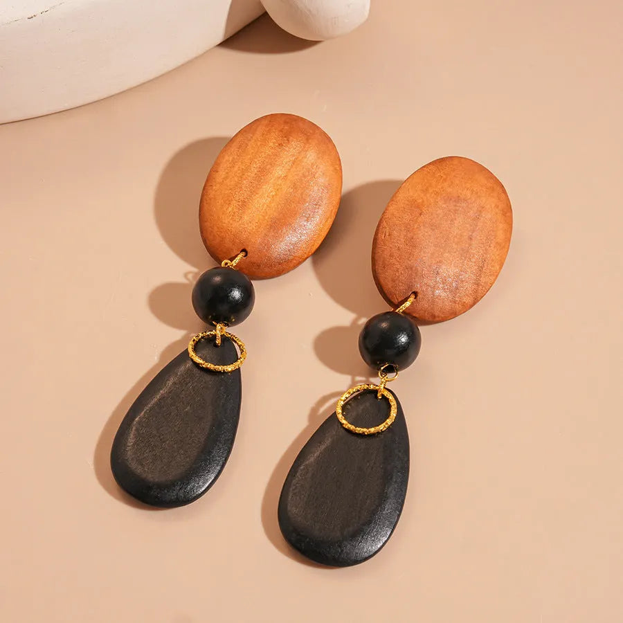 Pair of brown and black wooden elliptical retro style earrings on a silver backing.