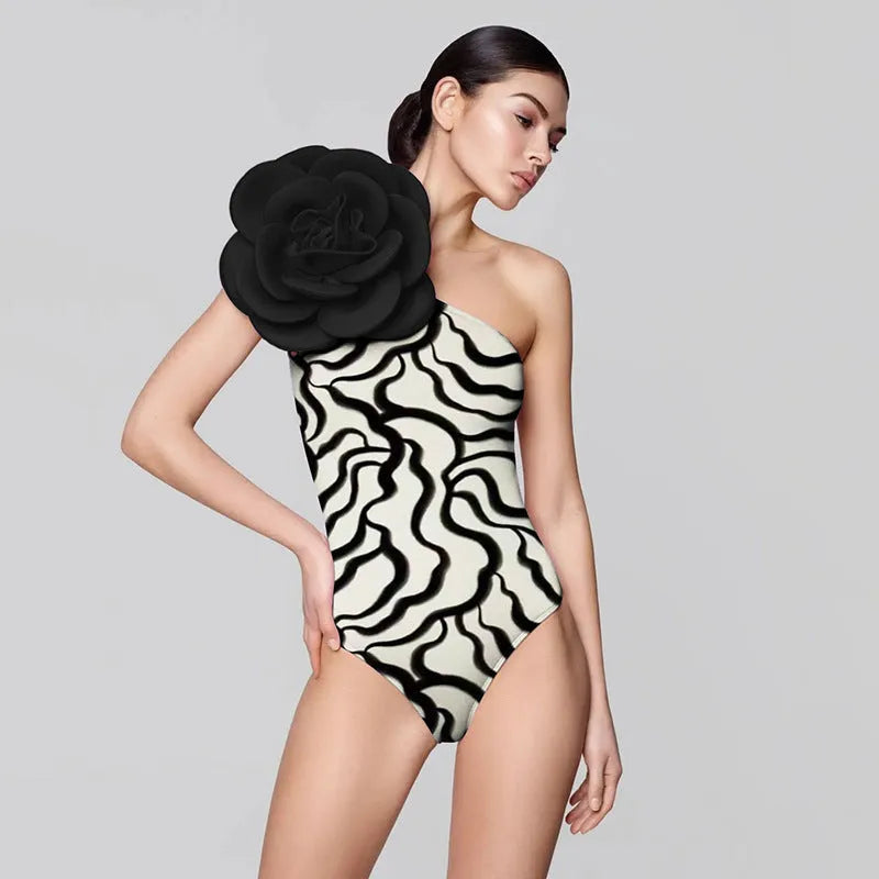 Black one-piece swimsuit with white three-dimensional flower design, form-fitting European American style.