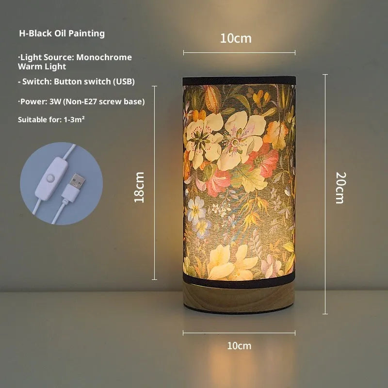 Creative floral fabric table lamp with remote control, warm LED light, black oil painting pattern on a bedside table