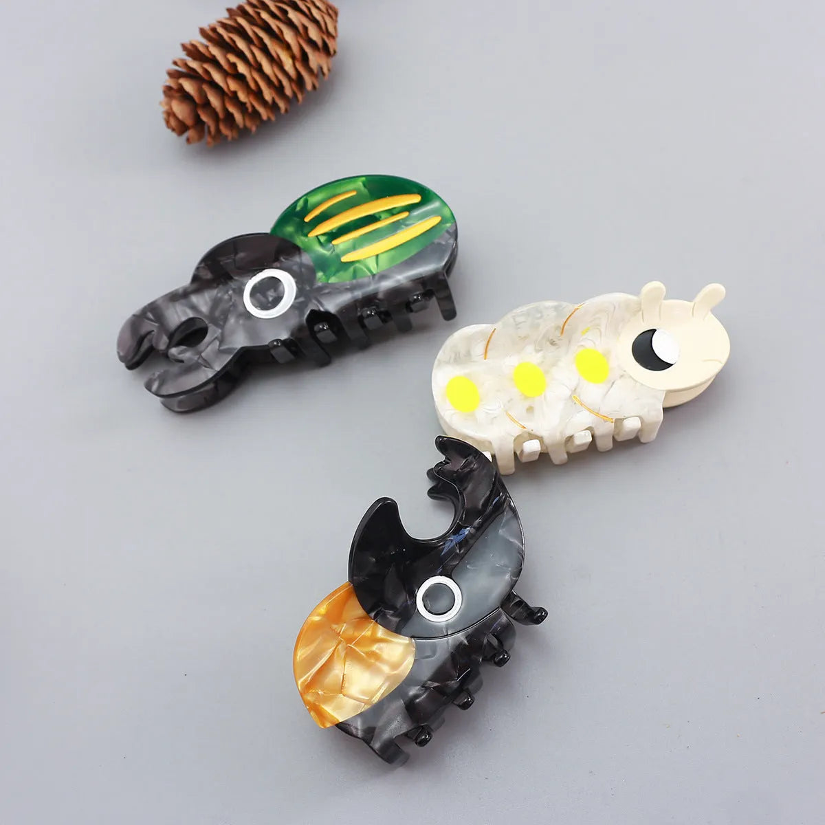 Handmade cellulose acetate beetle grip hair clip with cartoon caterpillar design in green, orange and white colours