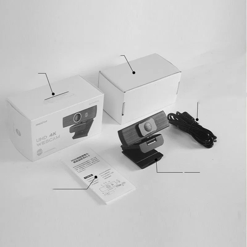 Black USB webcam with magnetic privacy cover on a desk next to a laptop.
