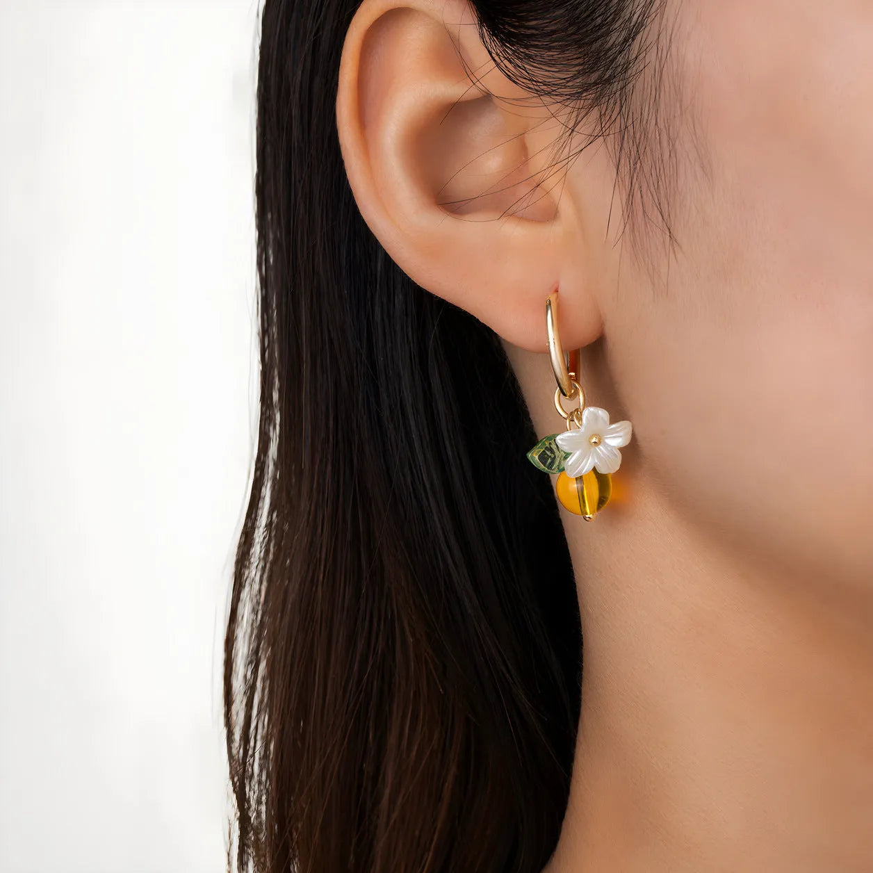 Pair of yellow acrylic sweet bee and honey fruit shaped earrings on a white background