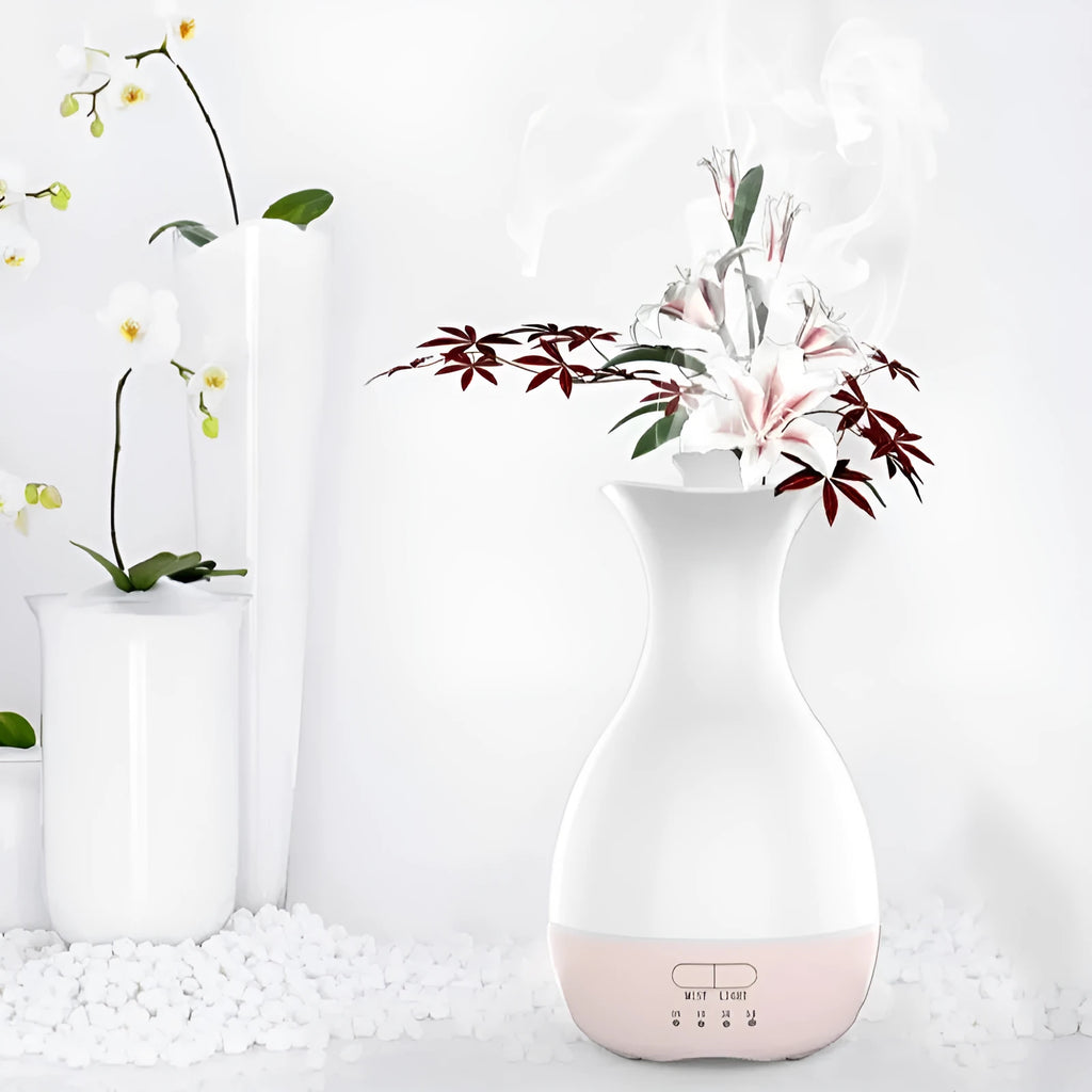 White or pink ultrasonic essential oil diffuser with water tank and multicolour LED night light on a table.