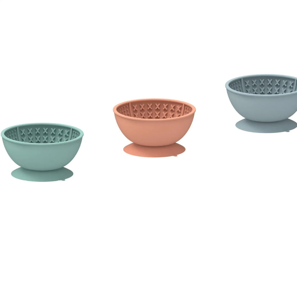 Cyan silicone dog bowl with raised licking mat texture and suction cup base on a floor.
