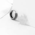 Silver geometric circular earrings made from twisted stainless steel stripes on a white background.