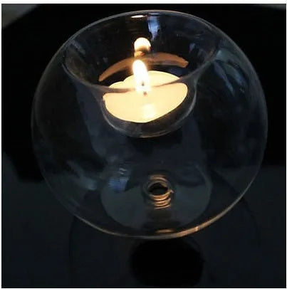 Handmade round hollow glass candle ball in three sizes on a table.