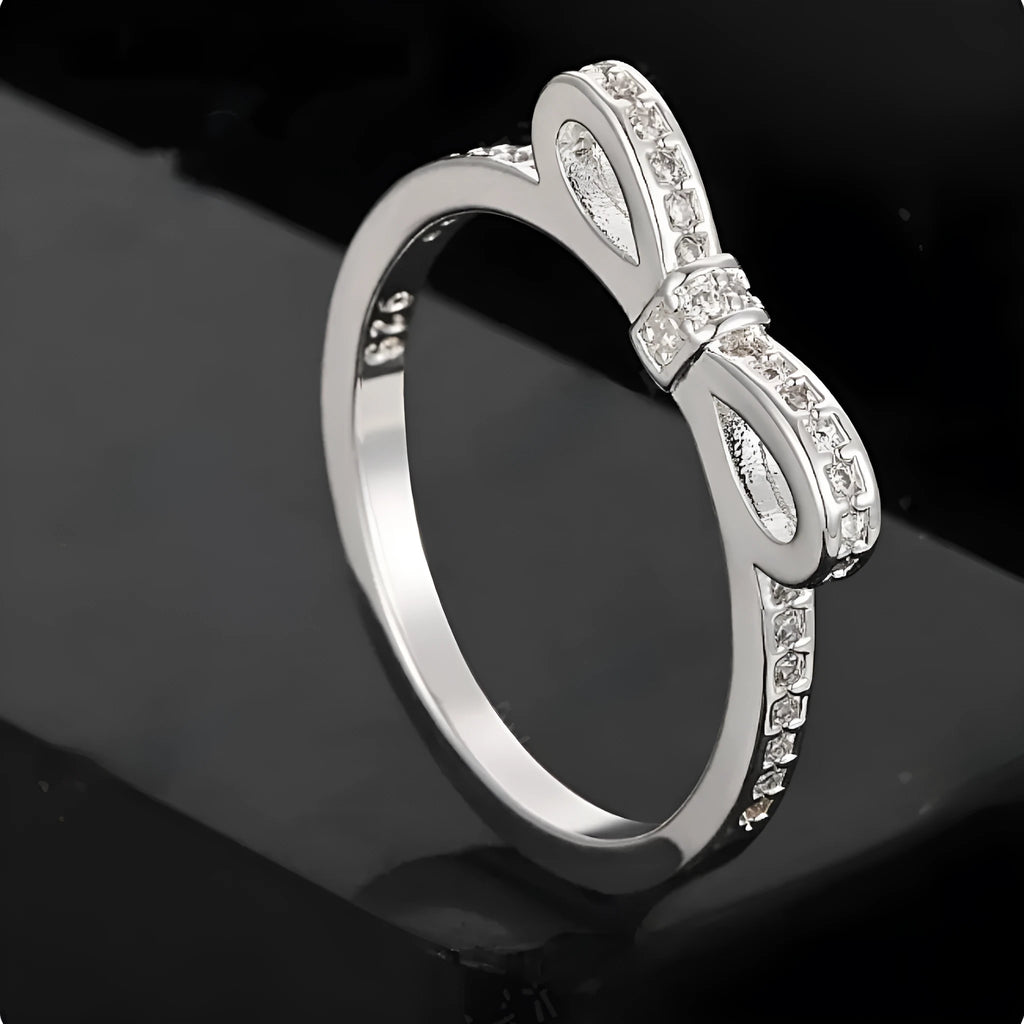 Silver bow-shaped ring with rhinestone detailing, shown in electroplated finish