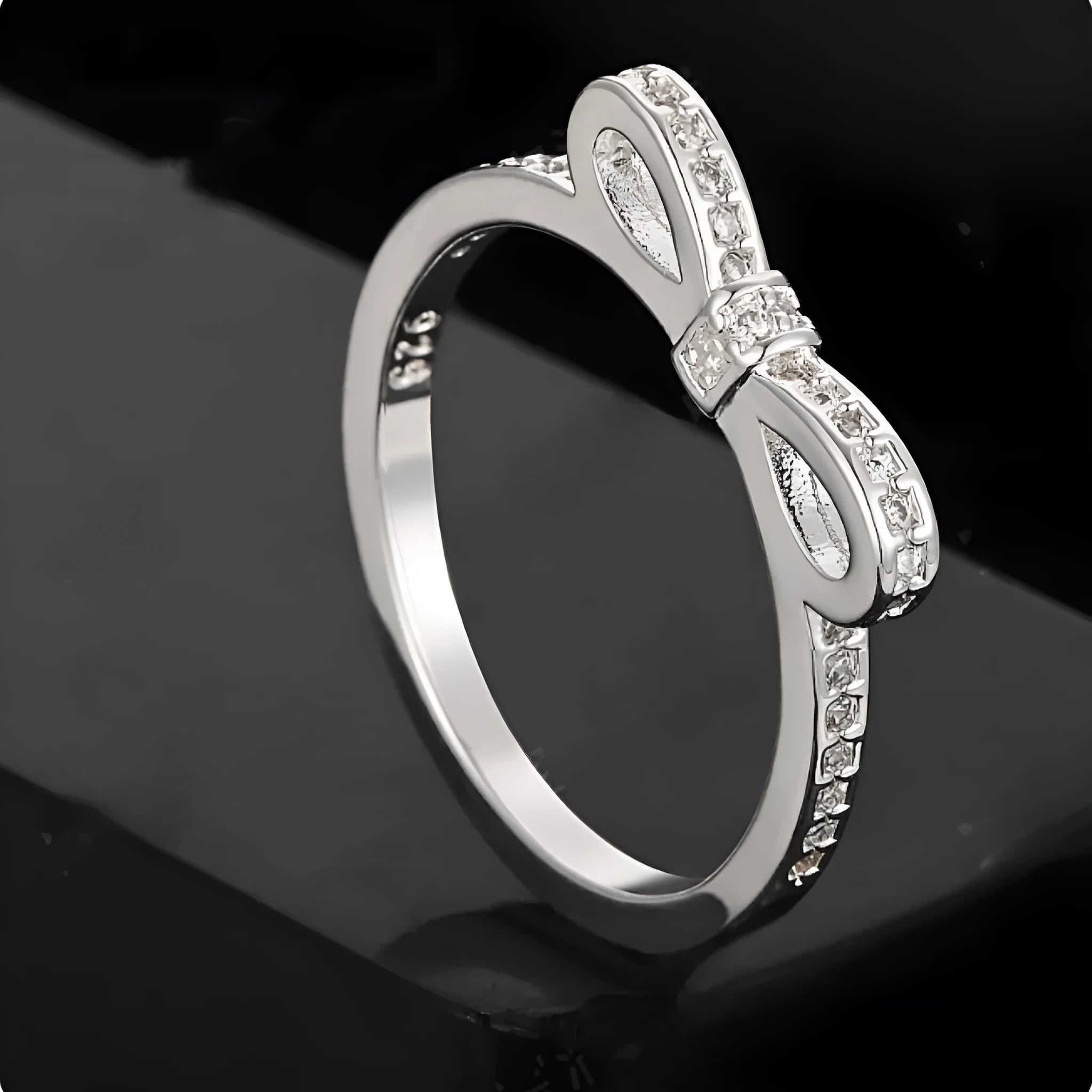 Silver bow-shaped ring with rhinestone detailing, shown in electroplated finish