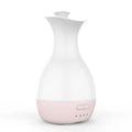 White or pink ultrasonic essential oil diffuser with water tank and multicolour LED night light on a table.