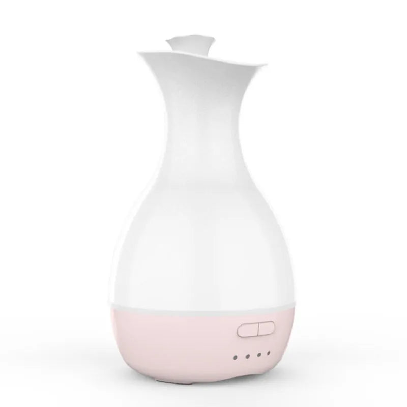 White or pink ultrasonic essential oil diffuser with water tank and multicolour LED night light on a table.