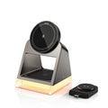 Black three-in-one magnetic wireless charger with night lamp charging phone, watch, and headset on a desk