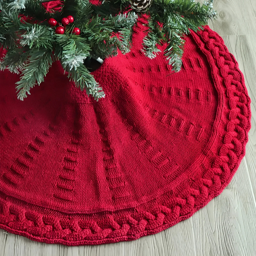 Red knitted wool Christmas tree skirt with 122cm diameter on floor under decorated tree
