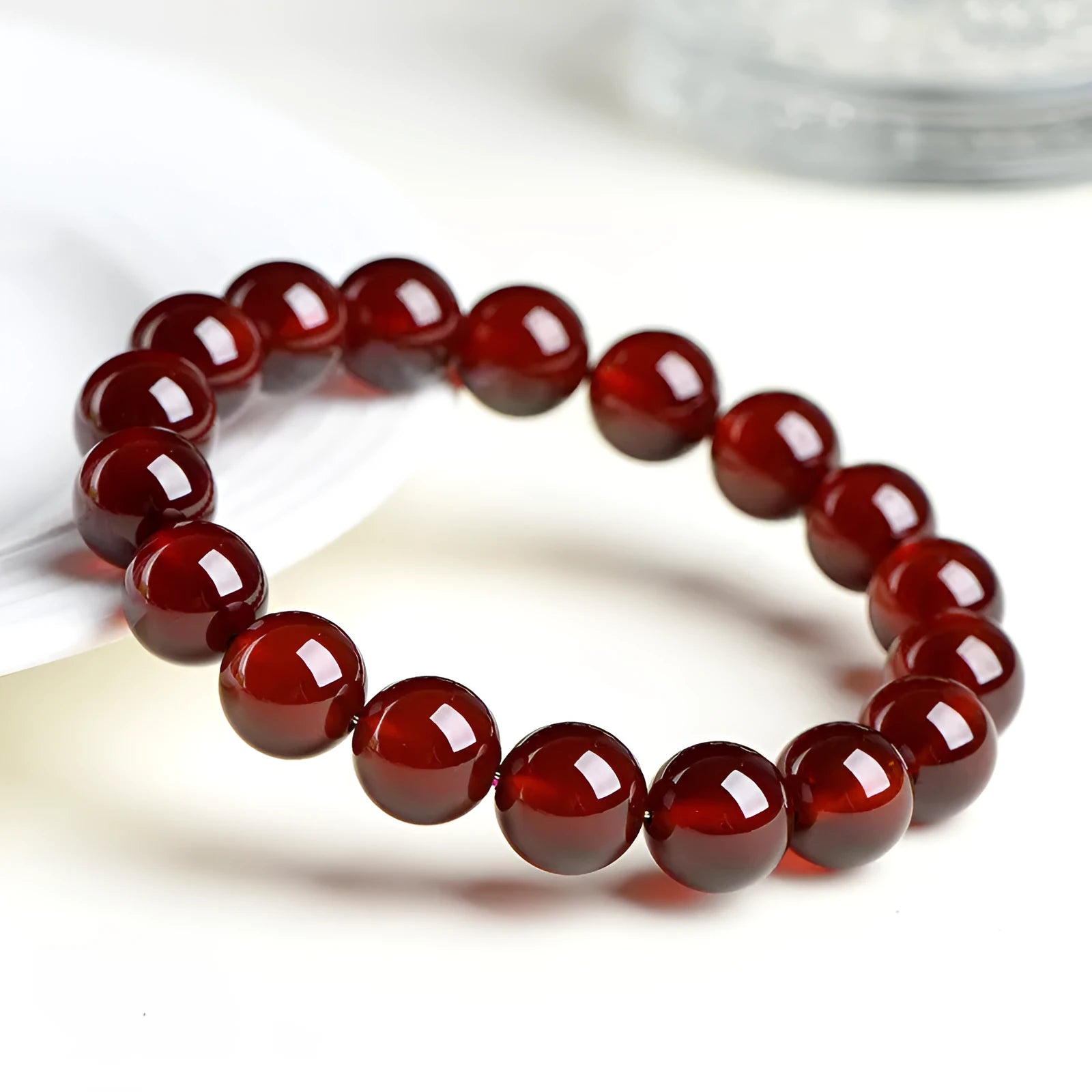 Natural orange red garnet ball bracelet with a silver Ruyi charm on a crystal beaded strand.