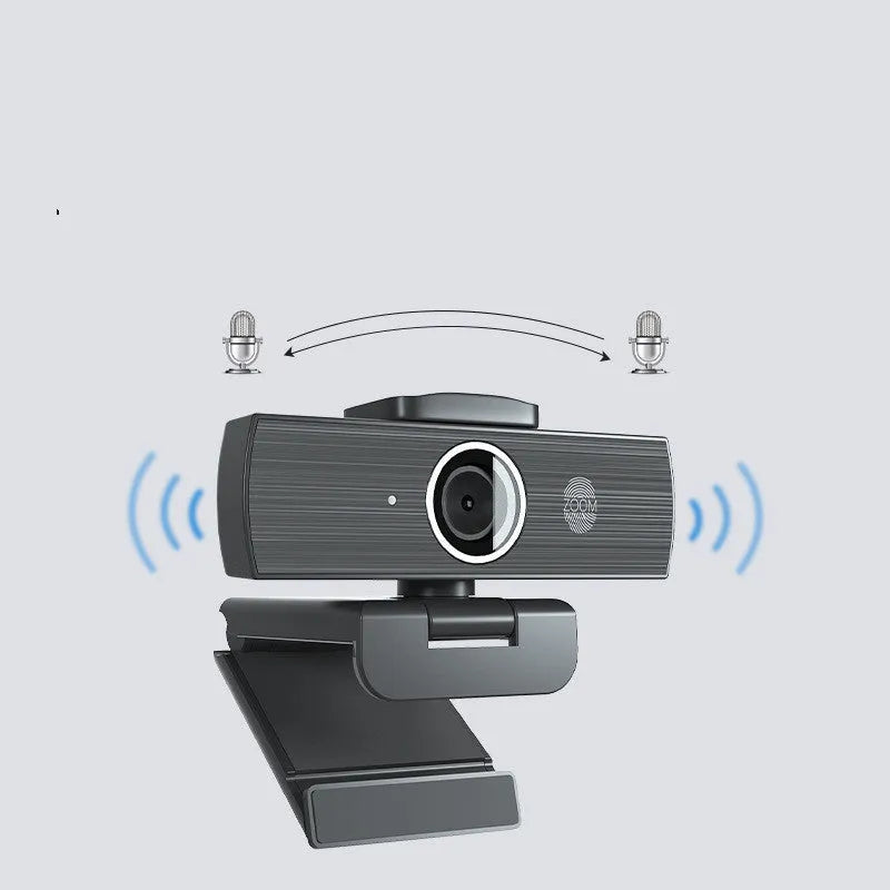 Black USB webcam with magnetic privacy cover on a desk next to a laptop.
