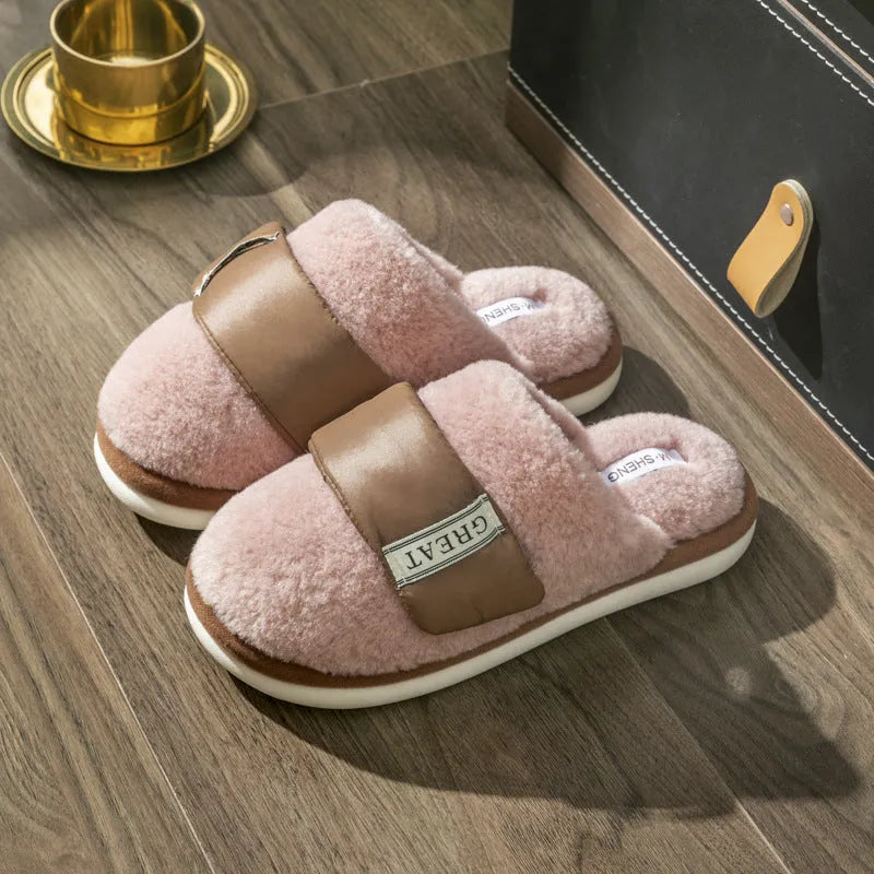 Women's beige plush slipper with Velcro strap and non-slip plastic sole on a wooden floor.