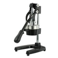 Black cast iron manual juice extractor with stainless steel strainer on a kitchen counter.