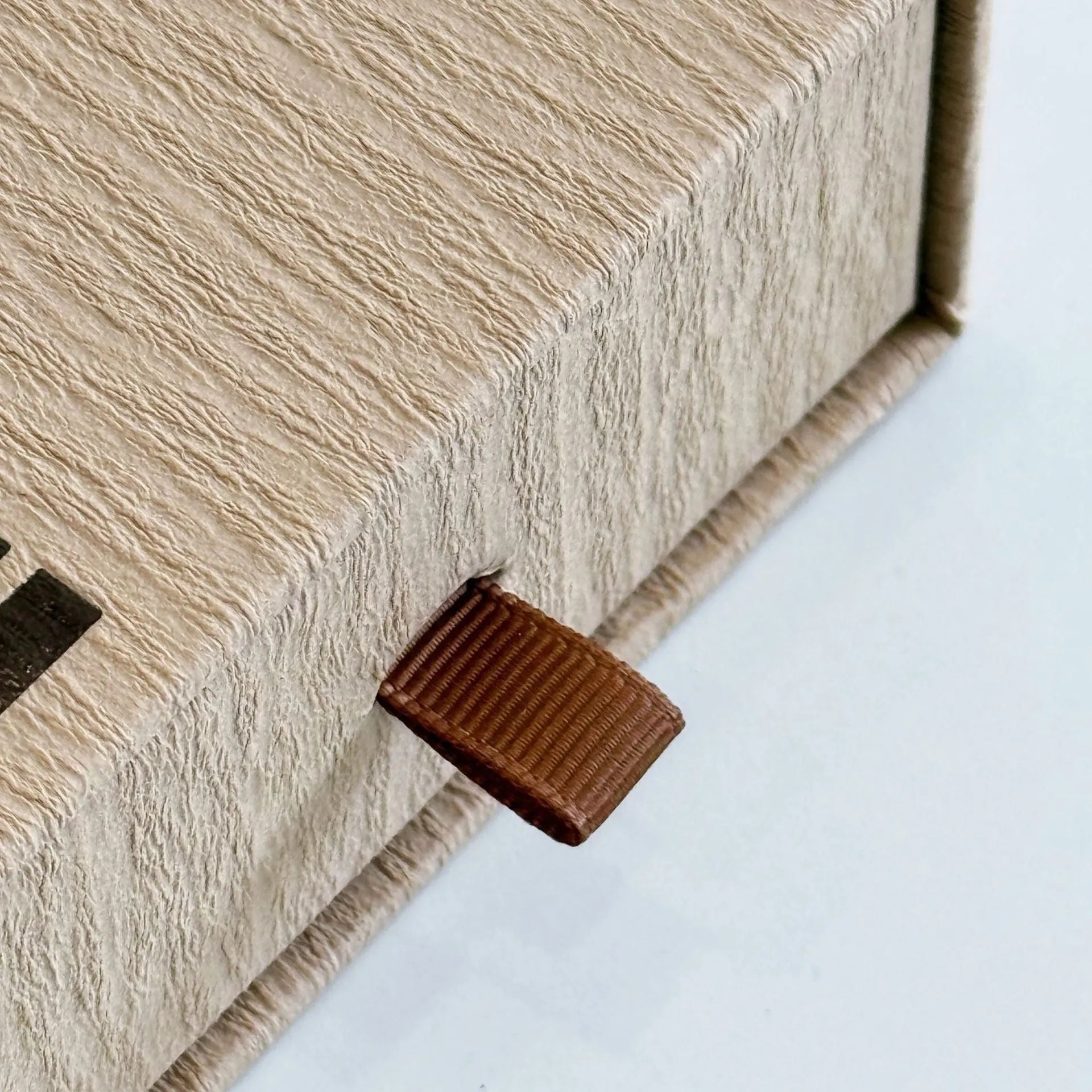 Beige brown cardboard drawer jewellery box with a storage bag beside it