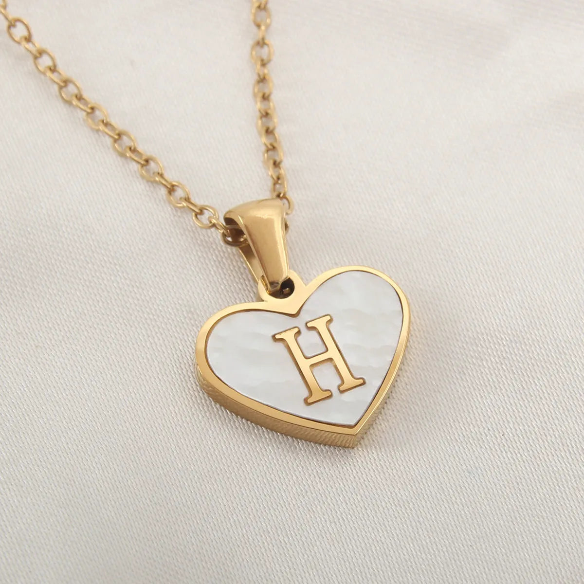 Gold plated heart-shaped necklace with a personalised initial letter and white shell detail on a 50cm adjustable chain.