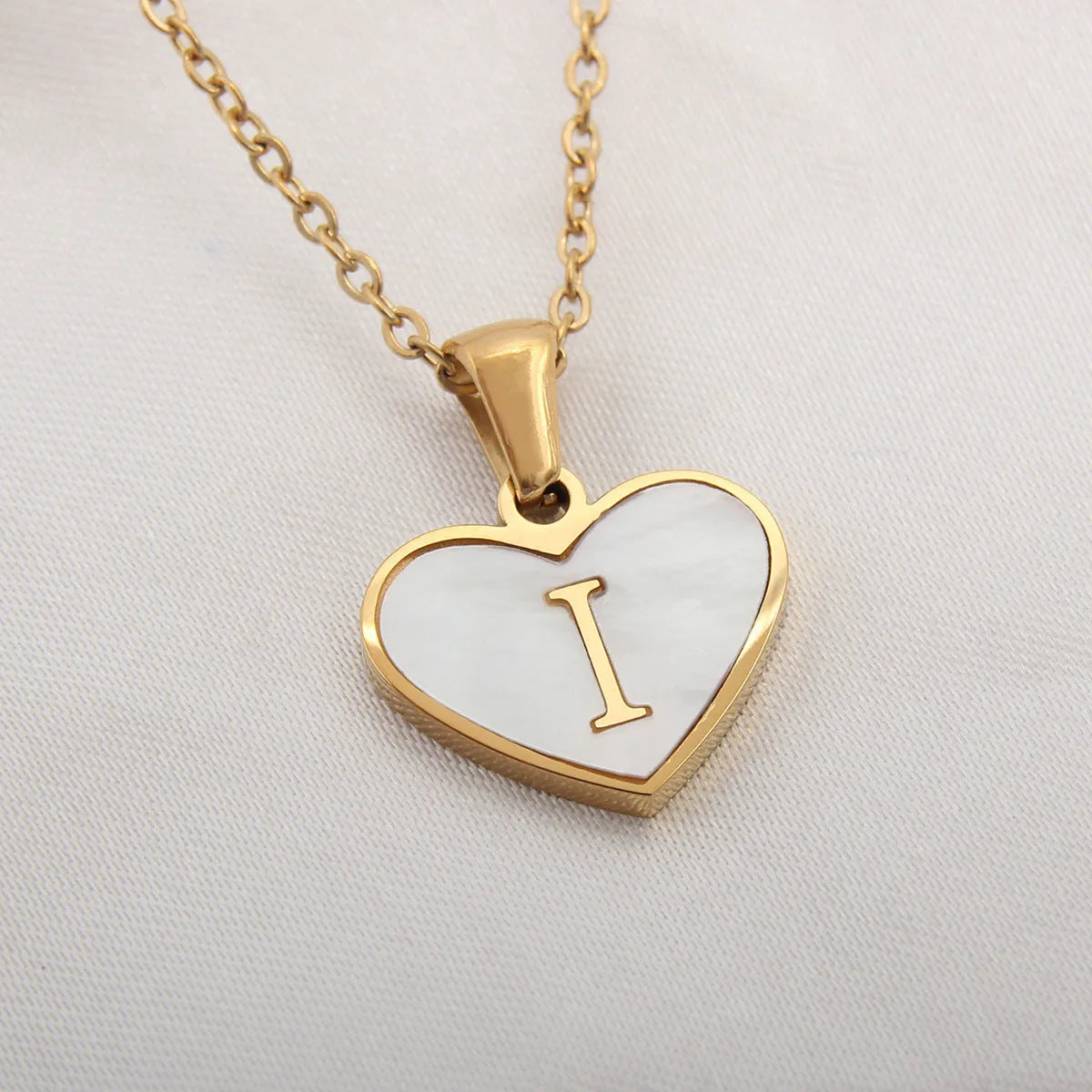 Gold plated heart-shaped necklace with a personalised initial letter and white shell detail on a 50cm adjustable chain.