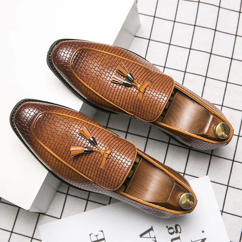 Men's black pointed slip-on leather shoes with a tassel detail on the low-top upper.