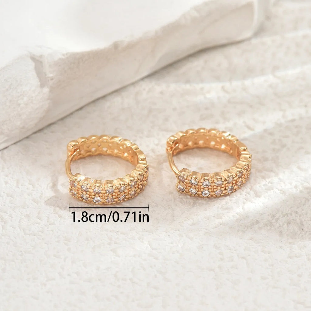 A pair of geometric pattern copper ear studs with round, dot, and ring design details.
