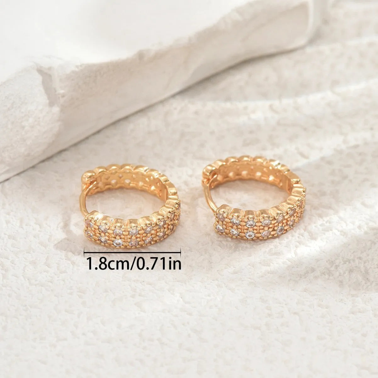 A pair of geometric pattern copper ear studs with round, dot, and ring design details.