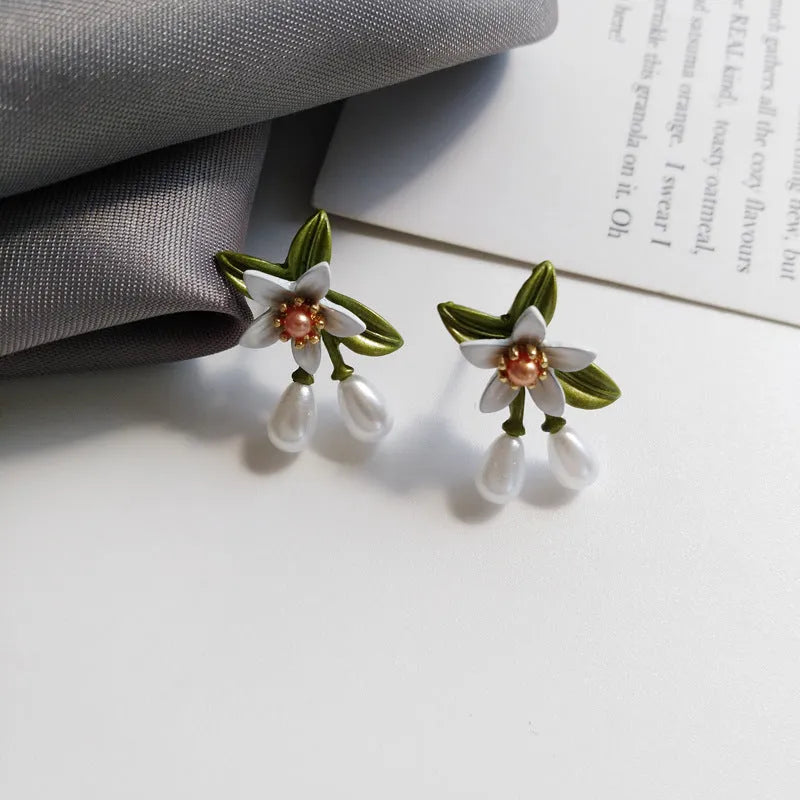 A pair of alloy camellia flower earrings for women, showing both the stud and clip styles.
