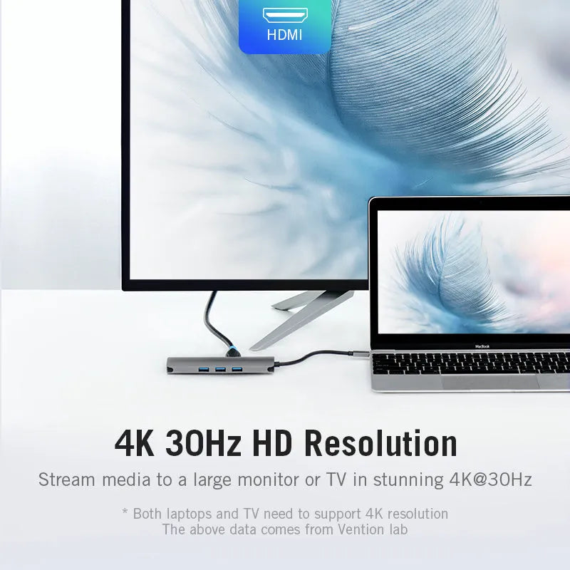 Deep grey USB-C to HDMI, USB 3.0, Ethernet, and card reader hub adapter on a desk.