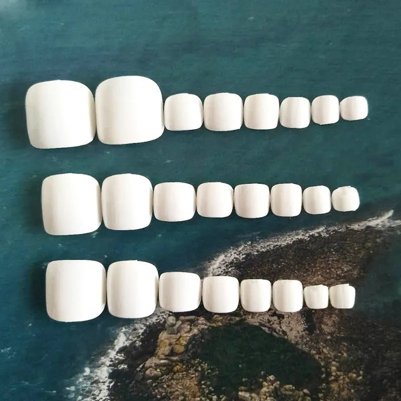 Set of white false toenails with a starry sky pattern and glue for application.