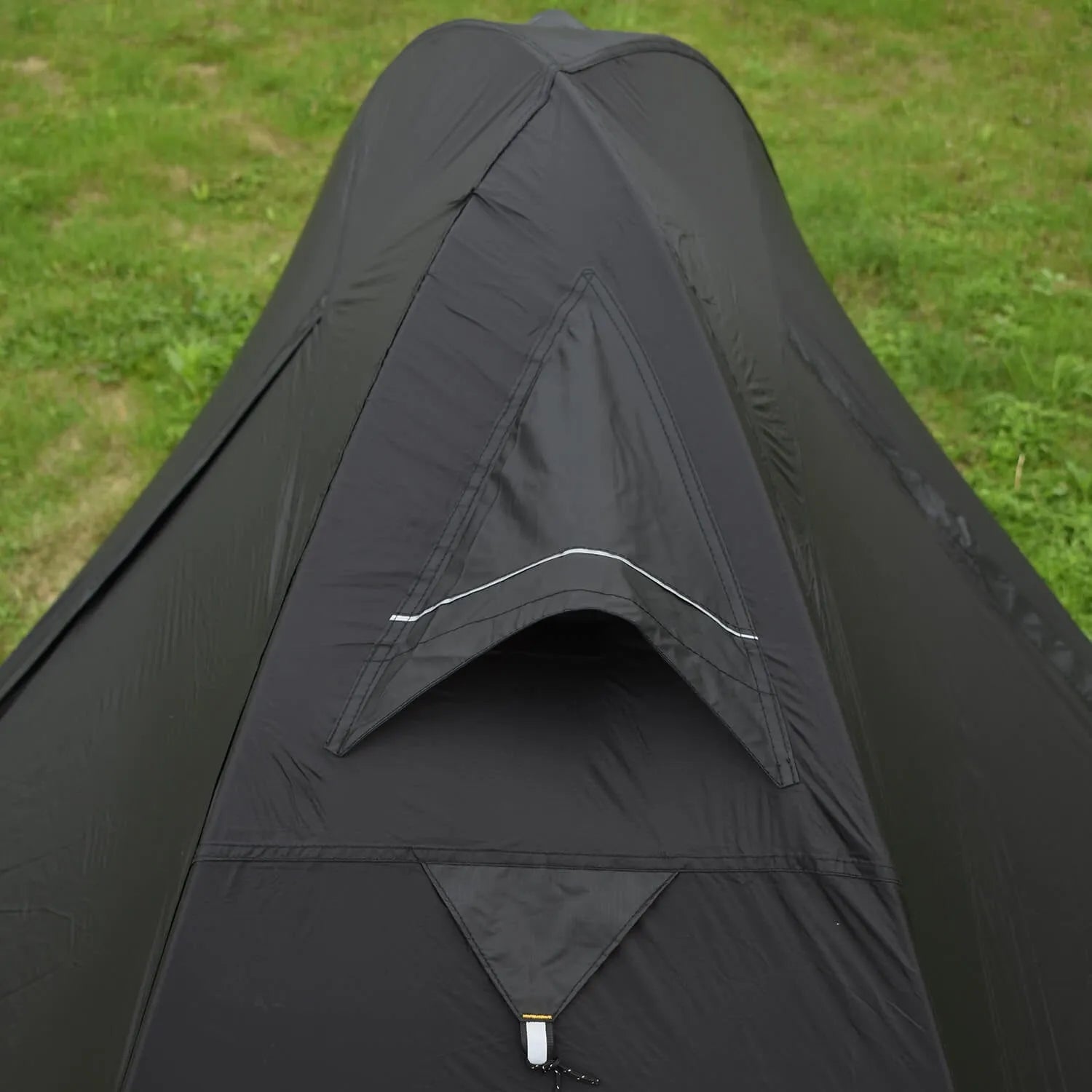Black single person hiking tent with aluminium poles pitched outdoors, showing double-layer design.