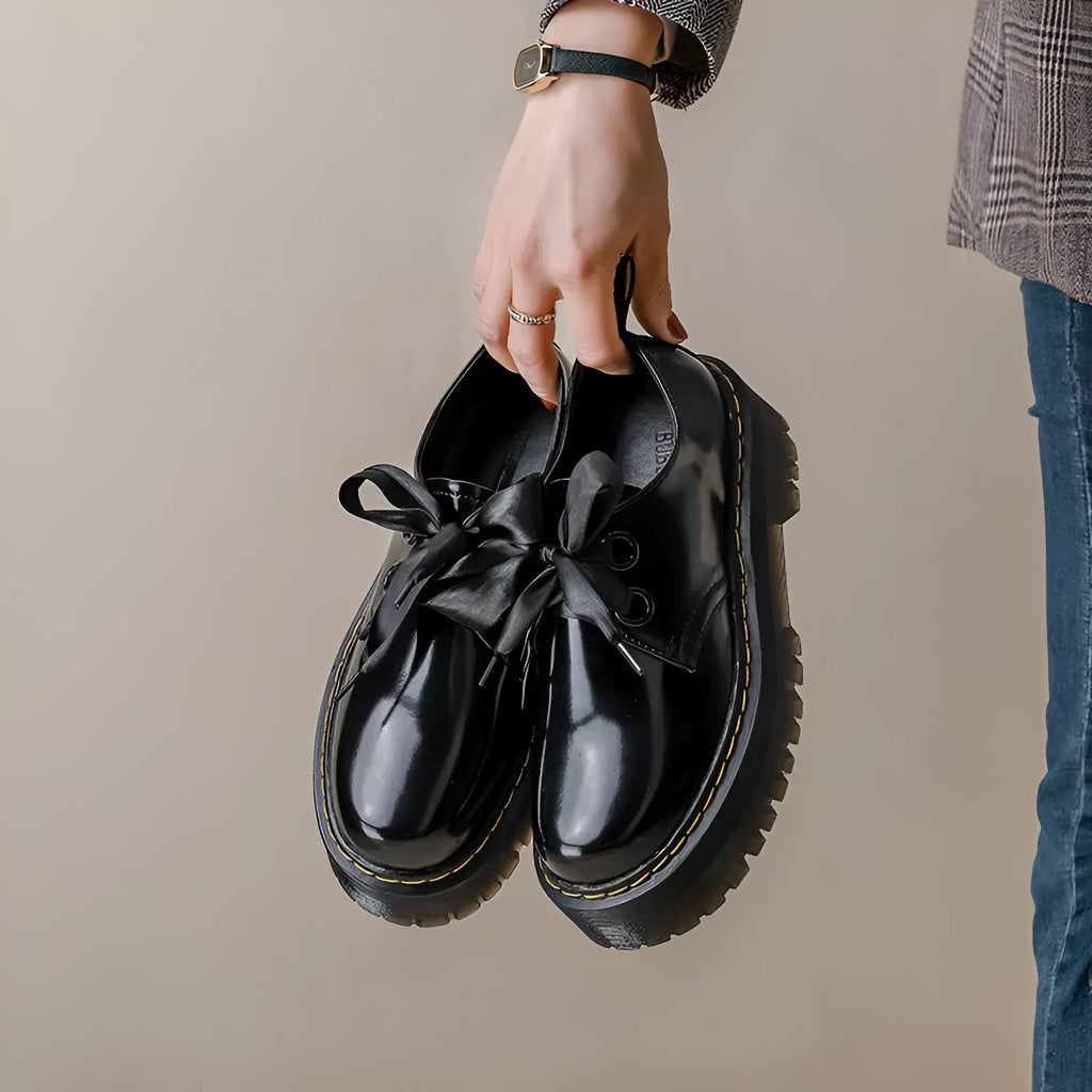 Women's thick-soled black shoes with cross strap and ribbon detail, lace-up closure