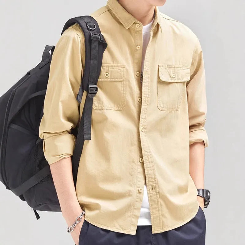 Man wearing a loose grey long sleeve shirt with a cardigan and overalls-inspired design