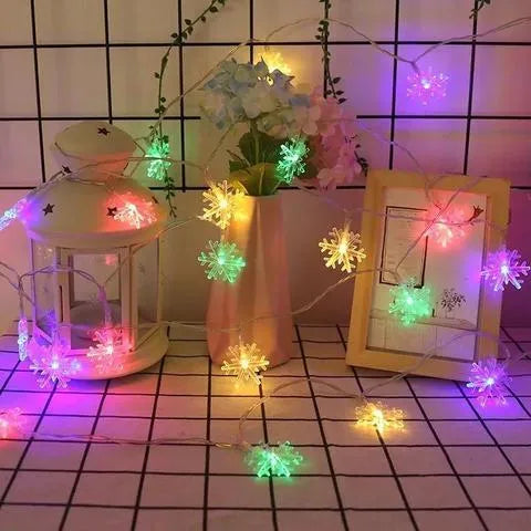 Battery powered LED snowflake string lights with star decorations lit on a dark background