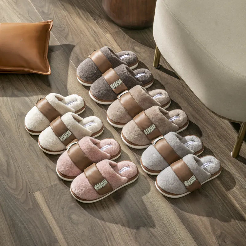 Women's beige plush slipper with Velcro strap and non-slip plastic sole on a wooden floor.
