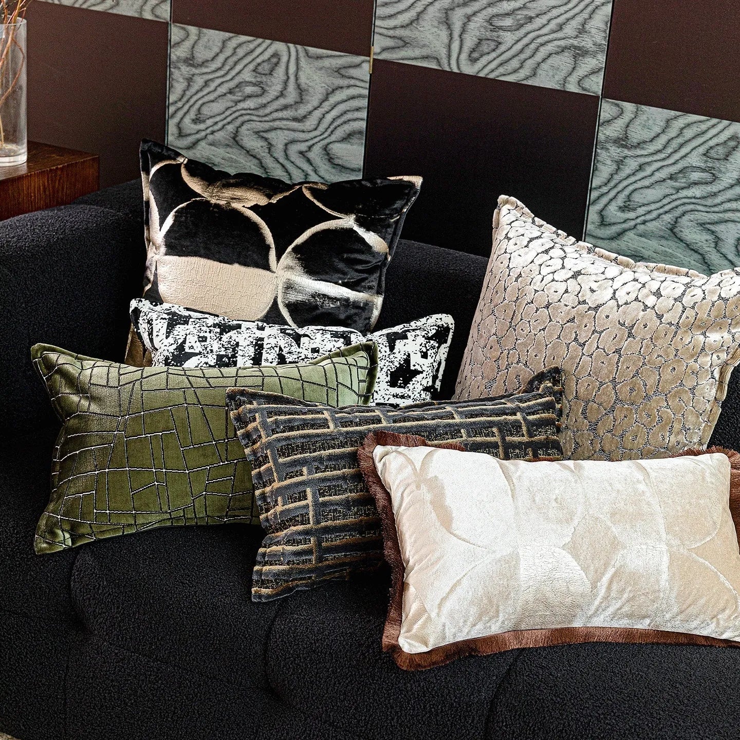 Black and gold abstract pattern decorative cushion cover on a grey sofa.