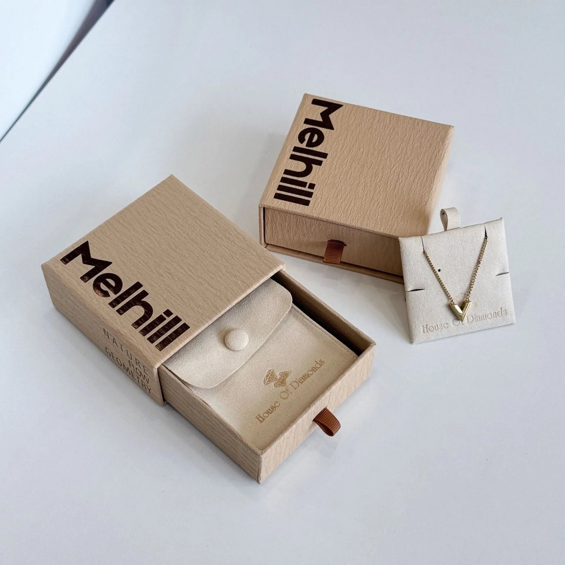 Beige brown cardboard drawer jewellery box with a storage bag beside it