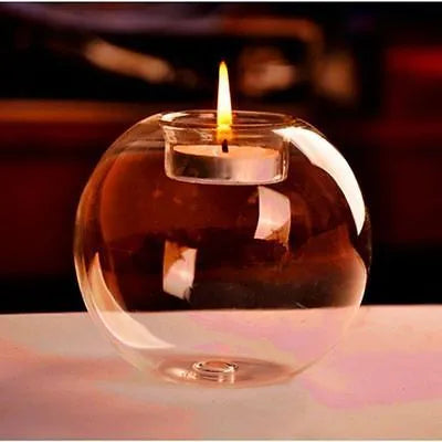 Handmade round hollow glass candle ball in three sizes on a table.