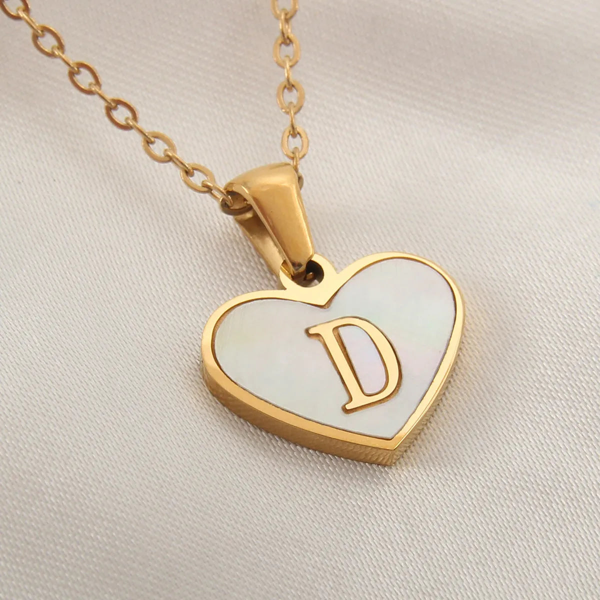 Gold plated heart-shaped necklace with a personalised initial letter and white shell detail on a 50cm adjustable chain.