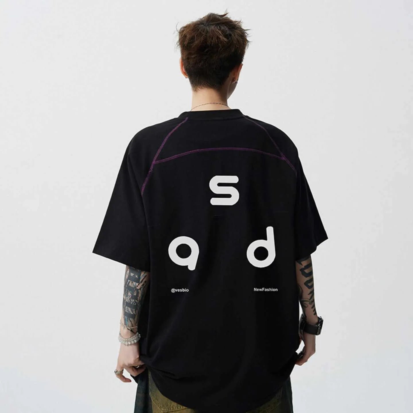 Men's loose-fit black cotton t-shirt with a white printed letter design on the front, showing short sleeves and a round neck.