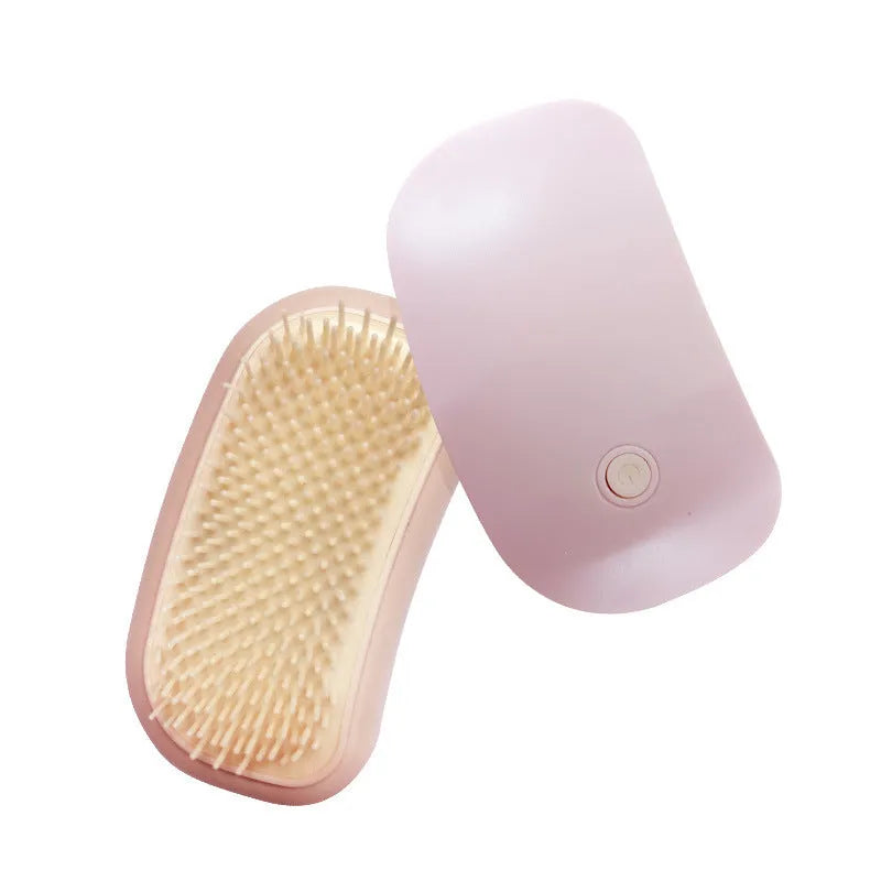 Pink handheld electric pet massage brush with soft TPE teeth on a white background.