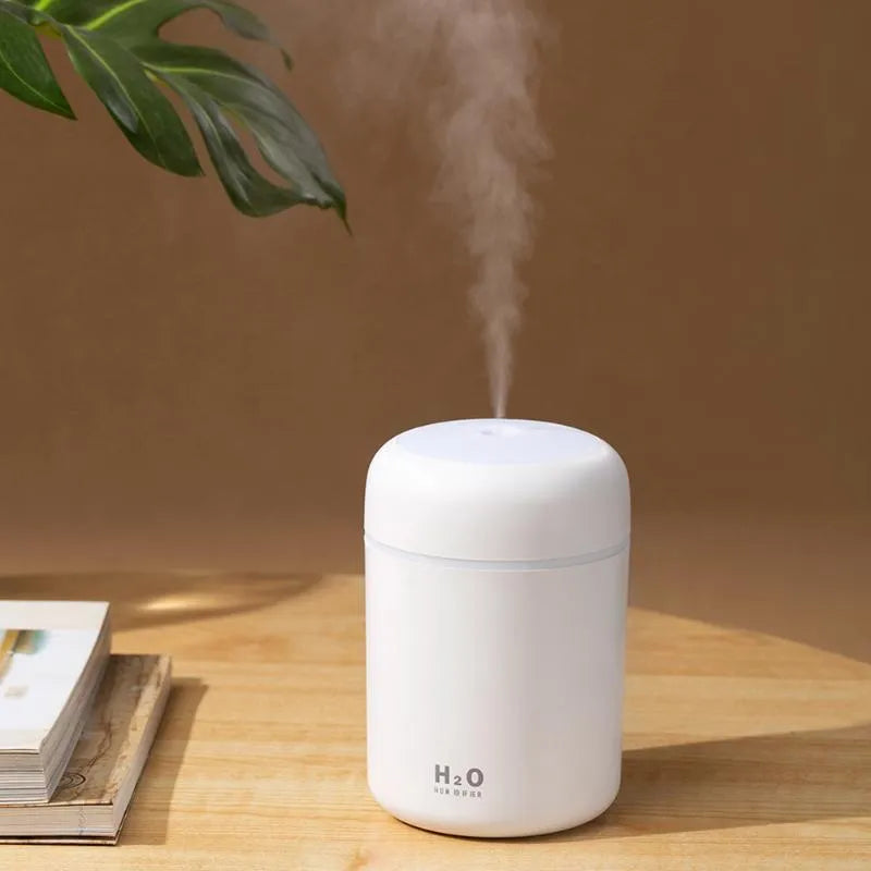 Pink USB-powered mini humidifier with colourful lights on a wooden desk