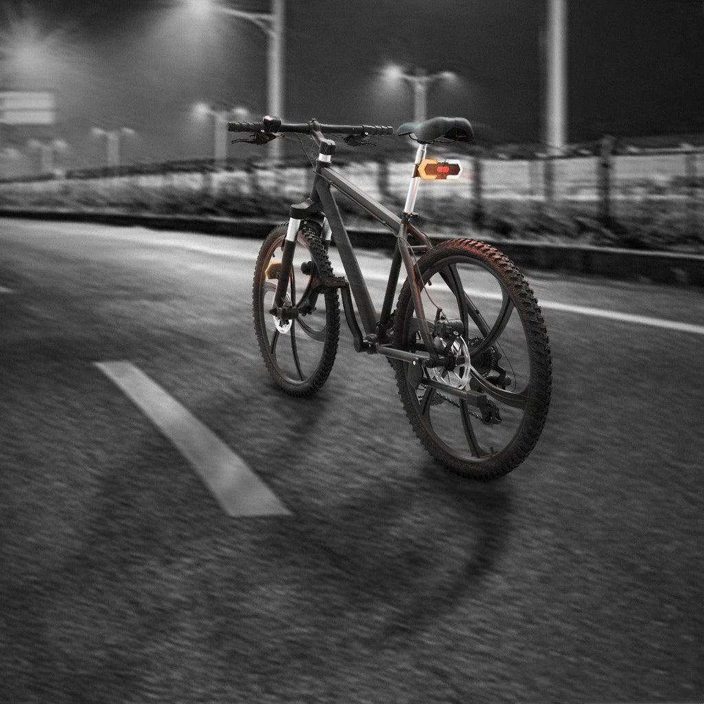 Black wireless bicycle turn signal set with remote control and USB charging cable on a bike frame